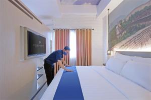 直葛Premiere Hotel Tegal的一位在旅馆房间做大床的人