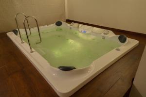 VayittiriMaple Ash Resort的铺有木地板,配有带绿水的浴缸。