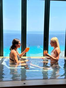 阿菲托斯Rigas Boutique Hotel & Spa的两个女人坐在游泳池里喝饮料
