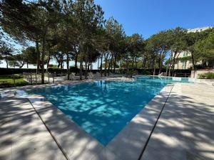 利尼亚诺萨比亚多罗Residenza Cristallo的拥有蓝色海水和树木的游泳池