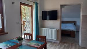 奥斯特罗沃Apartamenty Pod Lasem的客厅配有桌子、电视和床。