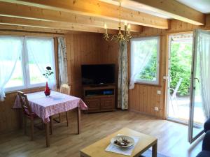 坎德施泰格Alpen Chalet的客厅配有桌子和电视