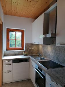 哈莱恩Haus Obweg - Postalm的厨房配有白色橱柜、水槽和窗户。