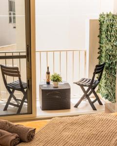 帕切维拉Modern Comfort - 2BR Apartment center of St Julians & Paceville的阳台配有两把椅子和一张桌子及一瓶葡萄酒