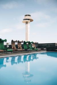 阿兰达Clarion Hotel Arlanda Airport Terminal的一个带椅子的游泳池和一个位于后面的控制塔