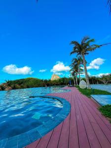 昆岛Orson Hotel & Resort Con Dao的一条木步道,旁边是种着棕榈树的水