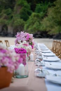 攀瓦海滩Cape Panwa Hotel Phuket的一张长桌,上面有紫色和白色的花