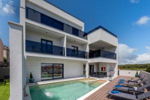 扎达尔Luxury Wellness & Spa Villa Depaja的白色的房子,设有游泳池和椅子