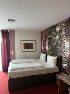 古梅尔斯巴赫阿戈塔酒店的卧室配有一张大床,墙上挂有绘画作品
