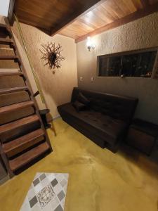 戈亚斯州上帕莱索Chalé tribal的客厅设有黑色沙发和楼梯。