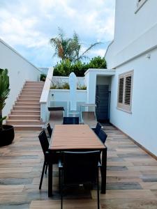佩斯科勒海滨Pescoluse Apartments的庭院设有木桌和椅子,设有楼梯