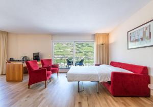 萨永Hôtel des Bains de Saillon的一间卧室配有一张床和两张红色椅子