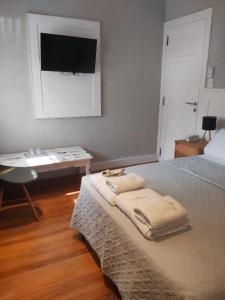 马德普拉塔Posada Güemes BOUTIQUE的一间卧室配有一张带书桌的床和一台墙上的电视。