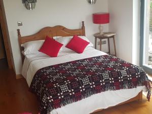 拉恩Powis Cottage的一间卧室配有一张带红色枕头的床