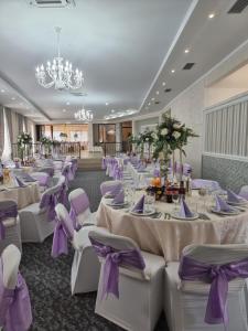 皮亚特拉-尼亚姆茨摩尔多瓦酒店的宴会厅配有白色桌子和紫色椅子