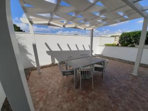 托雷拉皮罗Appartamento MaRi con piscina的庭院的白色遮阳伞下的桌椅