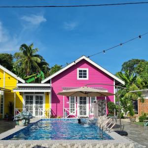哥打巴鲁Cheqma Tiny Chalet的粉红色的房子,前面设有一个游泳池