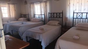 ZeerustSha-henné's Guesthouse的一间设有4张床、白色床单和窗户的客房