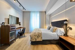 萨拉戈萨加泰罗尼亚支柱酒店的一间卧室配有一张床、一张书桌和一台电视