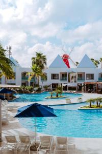 棕榈滩The Mill Resort and Suites的度假村前方的带椅子和遮阳伞的游泳池