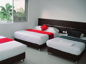 卡利AW Hotel Sport的一间卧室配有三张红色和白色床单