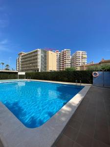 贝尼卡西姆Apartamentos Cumbremar en Benicàssim的一个大型蓝色游泳池,其建筑背景为: