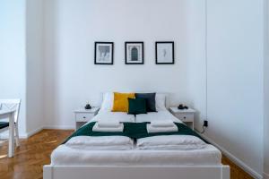 布达佩斯Budafoki Residence的白色房间一张白色的床,墙上有三张照片