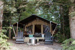 伍德斯托克Lumen Nature Retreat的树林里的帐篷,配有两把椅子和一张桌子