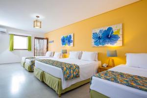 嘎林海斯港Armação Resort Porto de Galinhas的黄色墙壁的房间里设有三张床