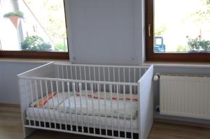 OsburgFerienwohnung Hoffmann的带2扇窗户的客房内的白色婴儿床