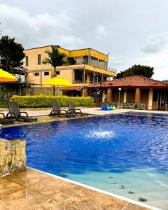 金巴亚Hotel Campestre Los Mangos的一座带椅子和遮阳伞的游泳池位于一座建筑旁边