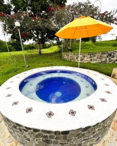 金巴亚Hotel Campestre Los Mangos的一把伞,坐在一个小型圆形游泳池旁