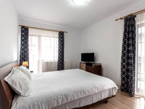 布拉索夫Apartamente Simona Brasov的一间卧室配有一张带窗帘的白色床和电视。