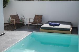 赫索尼索斯Hygge Suites的游泳池畔的一张床和椅子