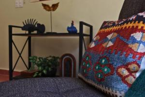 梅里达Casa Coco的一张沙发,上面摆放着小 ⁇ 枕头,坐在桌子旁边