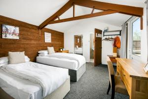 SistonBramley Barn near Bath + Hot tub的酒店客房配有两张床、一张书桌和一张书桌。