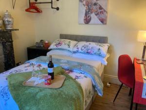 贝尔法斯特Mountroyal Victorian Studio Self Catering Apartment的一间卧室配有一张床,并备有带一瓶葡萄酒的托盘