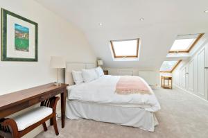 伦敦Family Home near Clapham Common by UnderTheDoormat的卧室配有一张床、一张书桌和窗户。