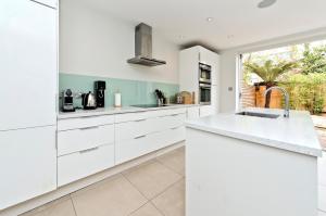 伦敦Family Home near Clapham Common by UnderTheDoormat的厨房配有白色橱柜和水槽