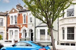 伦敦Family Home near Clapham Common by UnderTheDoormat的停在房子前面的蓝色汽车