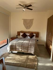 图卢姆Estudio completo en la selva的一间卧室配有一张带吊扇和地毯的床。