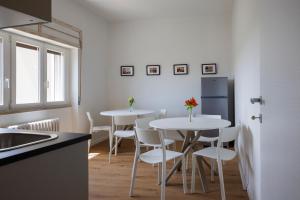 MafaldaB&B In Piazza的厨房配有2张桌子、白色椅子和冰箱