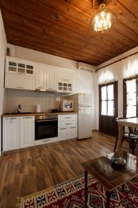 吉诺卡斯特Emblematic House Apartment 1的厨房配有白色橱柜和木制天花板