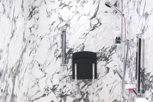 伦敦The Wellesley, a Luxury Collection Hotel, Knightsbridge, London的浴室内白色大理石墙和黑椅