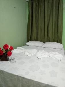 穆库热Pousada Recanto da Villa的一张铺有白色床单和红色鲜花的床