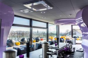 波恩prizeotel Bonn-City的餐厅设有紫色和黄色的椅子和窗户
