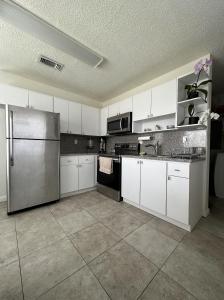 迈阿密Miami's Cozy Tropical Getaway的厨房配有白色橱柜和不锈钢冰箱