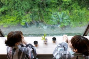 加贺山手香木酒店的两个孩子坐在一张桌子旁,望着窗外
