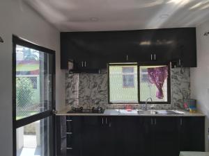 南迪Island Guesthouse - entire one bedroom unit with kitchen & a bathroom centrally located in Votualevu的厨房配有黑色橱柜、水槽和窗户。