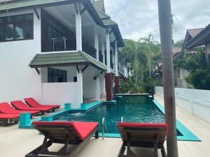哈德姚Amara Beach Resort Koh Phangan的游泳池旁的房屋设有红色椅子